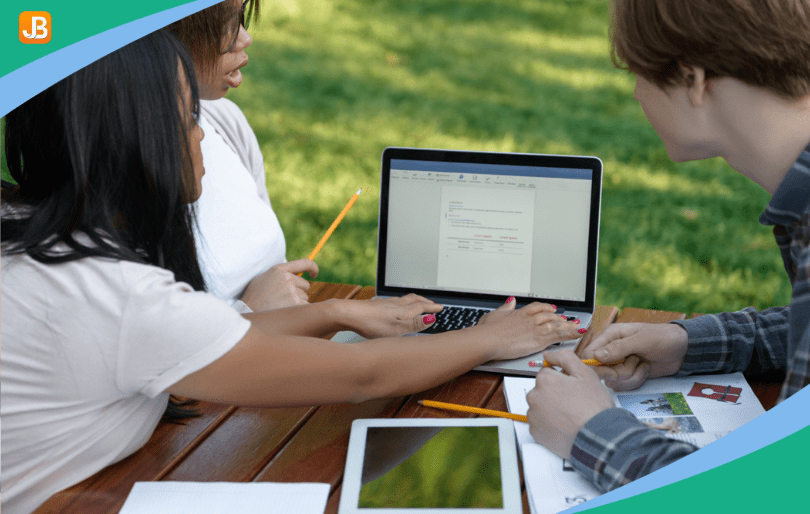 Camp staff gathered around a laptop and engaged in a discussion