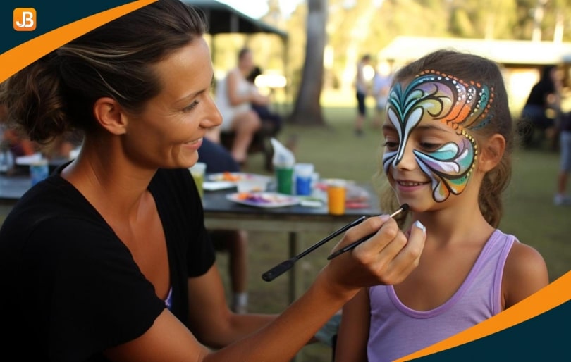 Woman painting a child's face with fall-themed designs at a festiva