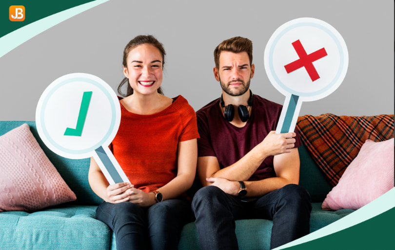 Two people on a sofa, one holding a checkmark and the other holding a cross