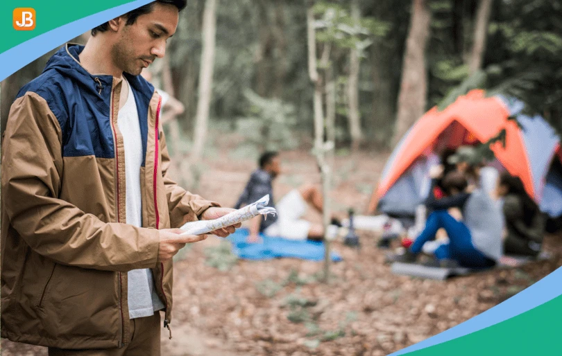 Man outdoors at a camp, reading a notebook to organize tasks