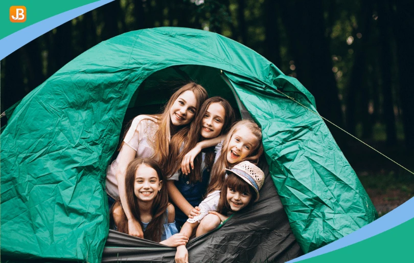 Children laughing in a tent, showcasing excitement and preparation for camp